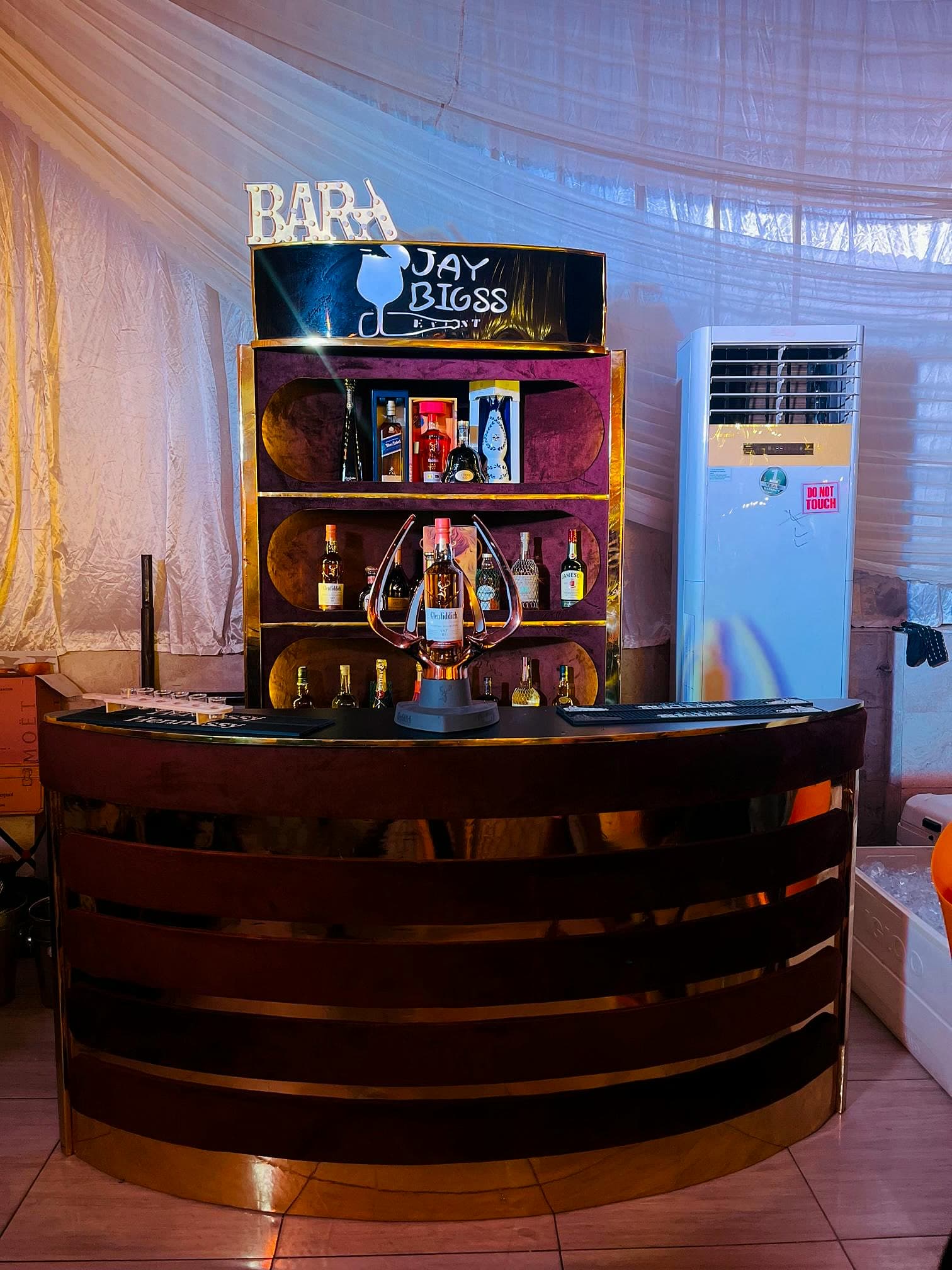 Branded Jay Bigss bar cart fully stocked with premium spirits and champagne under a lit BAR marquee sign