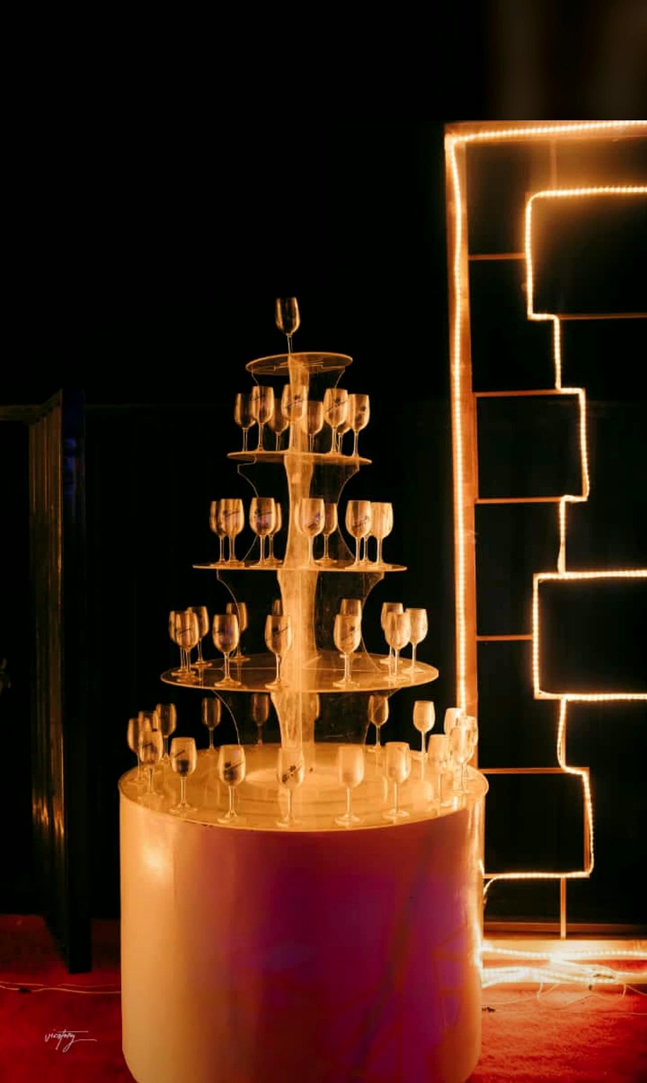 Tiered champagne glass tower fully set for a welcome toast beside an illuminated event sign